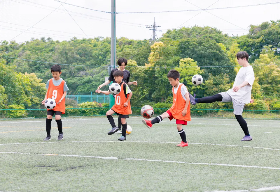 コーチと一緒にリフティングの練習をする子どもたち