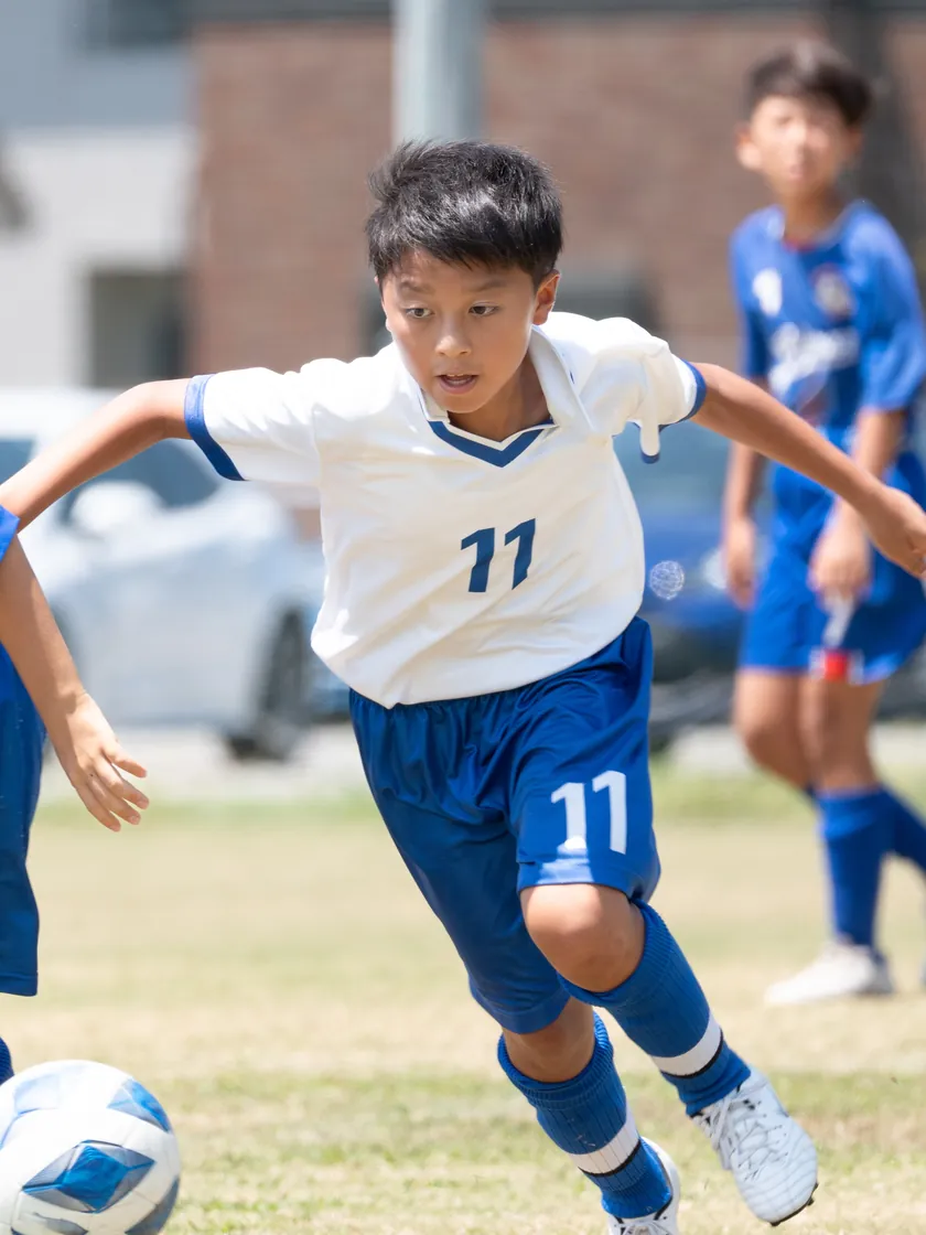 ドリブルで駆け上がる少年サッカーの選手