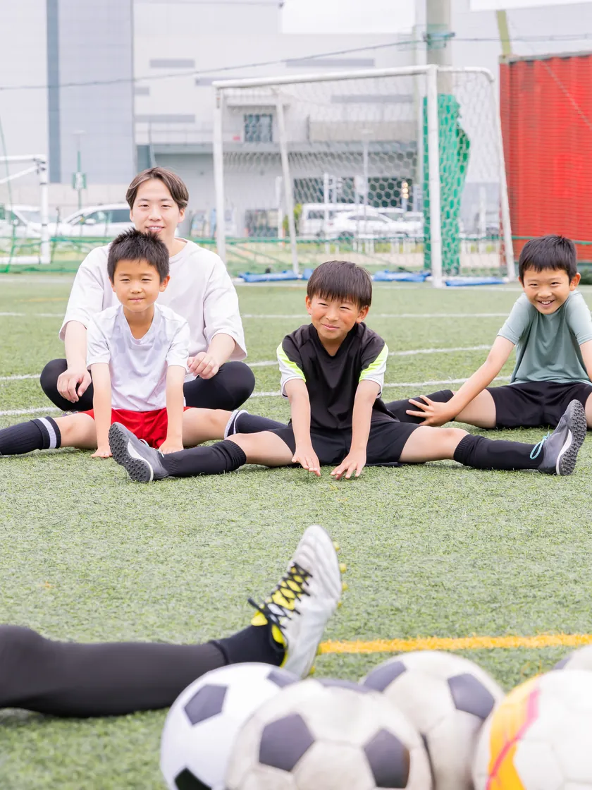 コーチと一緒にストレッチをする子どもたち